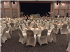 Winter wedding reception with white covered chairs tied with beige tool and napkins