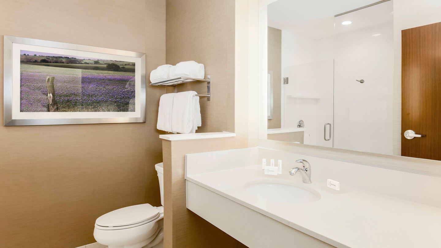 Inside an updated modern bathroom displaying a toilet with vanity sink and large mirror reflecting a