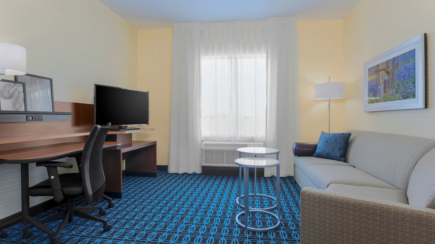 King guest room living area with a sofa work desk and chair on teal and dark brown carpet